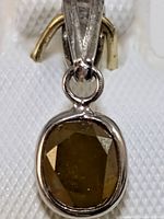 Close-up view of the cushion-cut natural fancy color diamond set in a 14K gold pendant, showing the front face of the diamond and part of the bale.