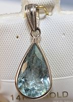 Close-up image of the pear-shaped light blue faceted aquamarine pendant set in 14k gold bezel with bail attached for necklace.
