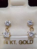 Front view of earrings on display card showing round and star-shaped CZ on 14K gold