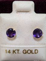 Front view of pair of 14K gold amethyst stud earrings on white display card