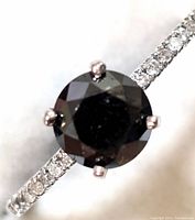 Close-up of round black diamond center stone with white diamond pavé band