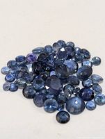 Close-up of an assortment of loose blue sapphires of varying sizes and shapes on a white background