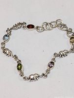 Close-up of the bracelet showing purple amethyst stone, red, blue, green, and yellow stones with silver elephant charms in between.