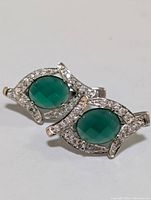 Pair of sterling silver earrings with green onyx center oval stones surrounded by cubic zirconia on a polished silver frame.