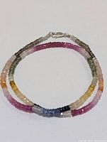 Full view of multi-color sapphire bead necklace arranged in a circle showing variation of gemstone colors and sterling silver clasp.