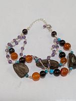 Sterling silver multi-gemstone bracelet shown lying flat with visible hemp clasp and extender chain with multiple colored stones and faceted smoky quartz.