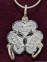 Close-up front view of the sterling silver four-leaf clover pendant showing embossed 'BEST FRIENDS' text on each leaf connected by rings.