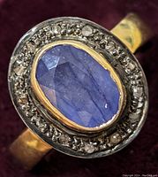 Close-up front view of sterling silver ring with oval sapphire center and diamond halo