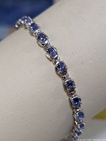 Close-up photo showing the sterling silver bracelet with cushion-cut tanzanite stones in prong settings.