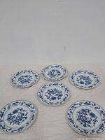 Six dessert plates arranged in two rows, showing the blue floral pattern on white ceramic with decorative border