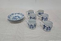 Six Blue Danube tea cups with matching four saucers laid out showing front and side of pieces.