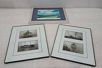 Three framed coastal photo arts, one light wood with a color photo, two black metal with black and white maritime photos.