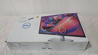 Photo of sealed Dell monitor box showing the brand logo and image of the 27-inch monitor on the front.