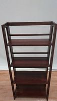 Front view of a foldable wooden bookcase with rich cherry brown finish and five shelves.