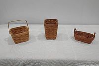 Front view of three woven baskets on white quilted surface