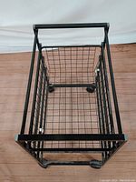 Top-down view showing the interior wire grid pull-out basket shelf and caster wheels beneath the metal frame.