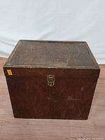 Full view of the small wooden trunk showing overall used condition and rectangular shape.