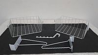 Two white wire slide-on baskets with open wire grid design on a black surface.