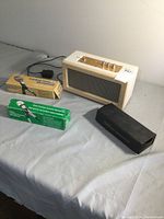 Overall photo of the Sharper Image amplifier and three microphones with two still in packaging and one in a case, showing all items included in the lot.