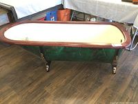 Side view showing green faux-marble exterior, wood rim and claw feet