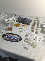 Wide view of mixed collection on table including Millennium coin set, Olympic coins, Obama sets, foreign coins, and brooch.