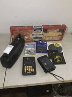 View of all items on table including red box guitar, electronic poker device, recorder, tapes and records