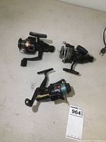 Three open face fishing reels arranged on a white surface showing size and design differences.