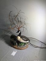 Front and side view of ceramic goose figurine with fibre optic light tree on wooden base. Includes two adult geese and three goslings.