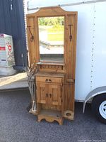Front view of the solid pine hall stand showing the mirror, hooks, drawer, cabinet, and umbrella holders.
