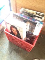 Red milk crate filled with packaged adult Halloween costumes and wigs.