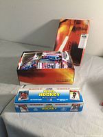 Photo of the open shoe box filled with various open packs of hockey cards, with the Pulse II box set behind it showing a red and black design.