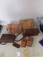 Photo showing the main lot of four leather purses, wallet and pouches arranged on a table.