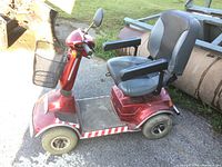 Left-side view of red mobility scooter showing seat, armrest and footboard