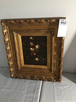 Photo of the framed oil painting showing the floral composition and ornate frame.