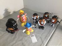All 6 Potato Head figures arranged on a gray cloth background including KISS figures, Darth Vader, Mrs. Potato Head, and small figure