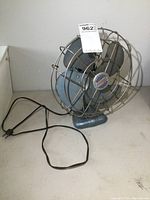 Full view of vintage Torcan metal fan showing blades, grille, base, and power cord.