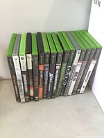 17 Xbox and Xbox 360 game cases standing upright showing titles on spines and cover art