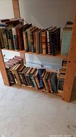 Books on wooden shelves arranged vertically, cover spines visible. Shows assortment and condition of books.