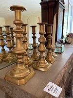 Photo of six brass candle holders arranged on a surface showing classic design and patina.