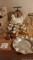 Overview photo displaying the hen on nest milk glass casserole, egg cups, condiment bottles, metal bell, and part of the food weight scale.