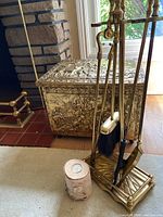 Side angle of firewood box with embossed classical or mythological figures and ornate details.