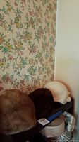 Three women's fur hats positioned on a shelf against floral wallpaper, showing size and color differences.