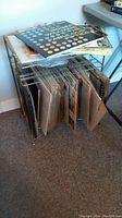 Top-down photo showing stack of assorted LP records on a metal record rack with vertical dividers, records packed tightly.