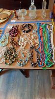Wide view of all necklace and earring sets displayed on table showing color and style variety