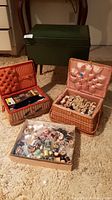 Photo showing the green sewing stool and two wicker sewing baskets open with spools and sewing accessories inside, plus a flat box of assorted spools.