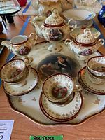 Full view of the tea set arranged on the tray showing the teapot, sugar bowl, creamer, cups, and saucers. Highlighting the classical art style and gold accents.