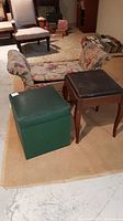 Overall view of vintage floral-patterned storage bench with two storage stools, one green and one brown wooden-legged