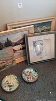 Four framed artworks and two decorative plates on carpet, showing lot contents including Robert Bateman artwork.