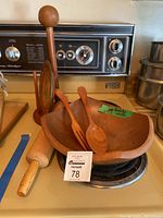 View of entire wooden kitchen accessories set on stove background showing bowl, serving fork and spoon, rolling pin, plate and paper towel holder.