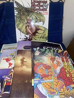 A group of convention programs featuring colorful anthropomorphic artwork, including the autographed book 'Dragons Myths & Mayhem' by Tommy Castillo propped up behind the program booklets.
